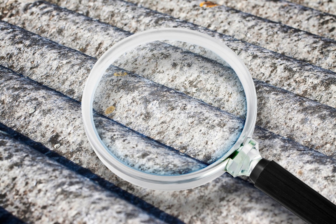 Analysis of the compounds of a dangerous asbestos roof panels - concept image with magnifying glass